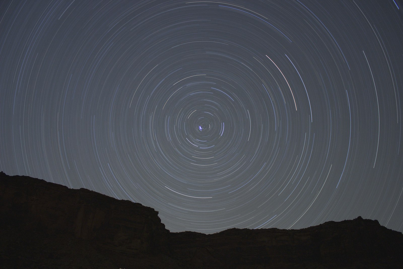 A long-exposure night sky showing circular star trails around the pole star
