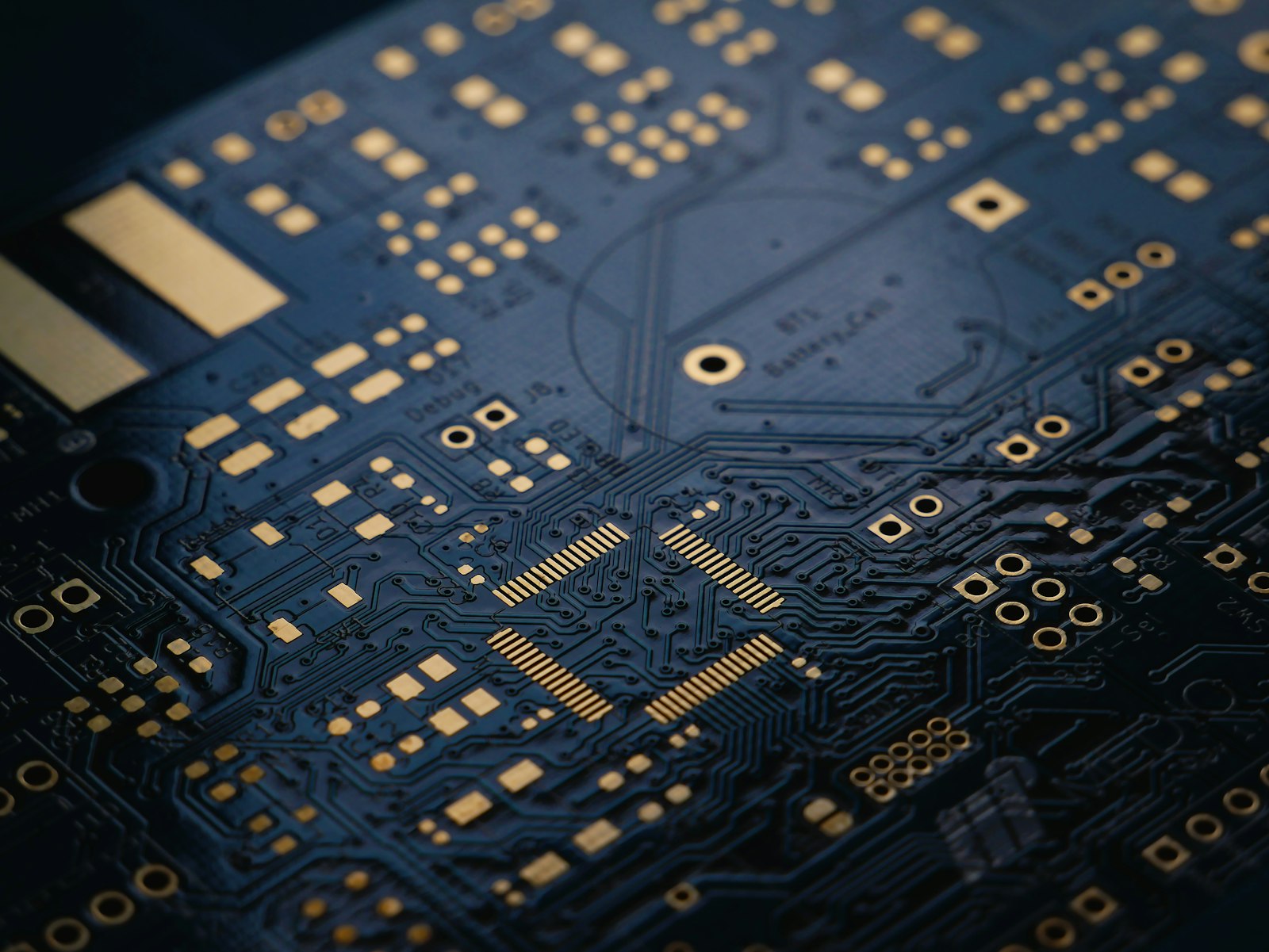 A dark blue printed circuit board with fine gold traces, photographed in macro