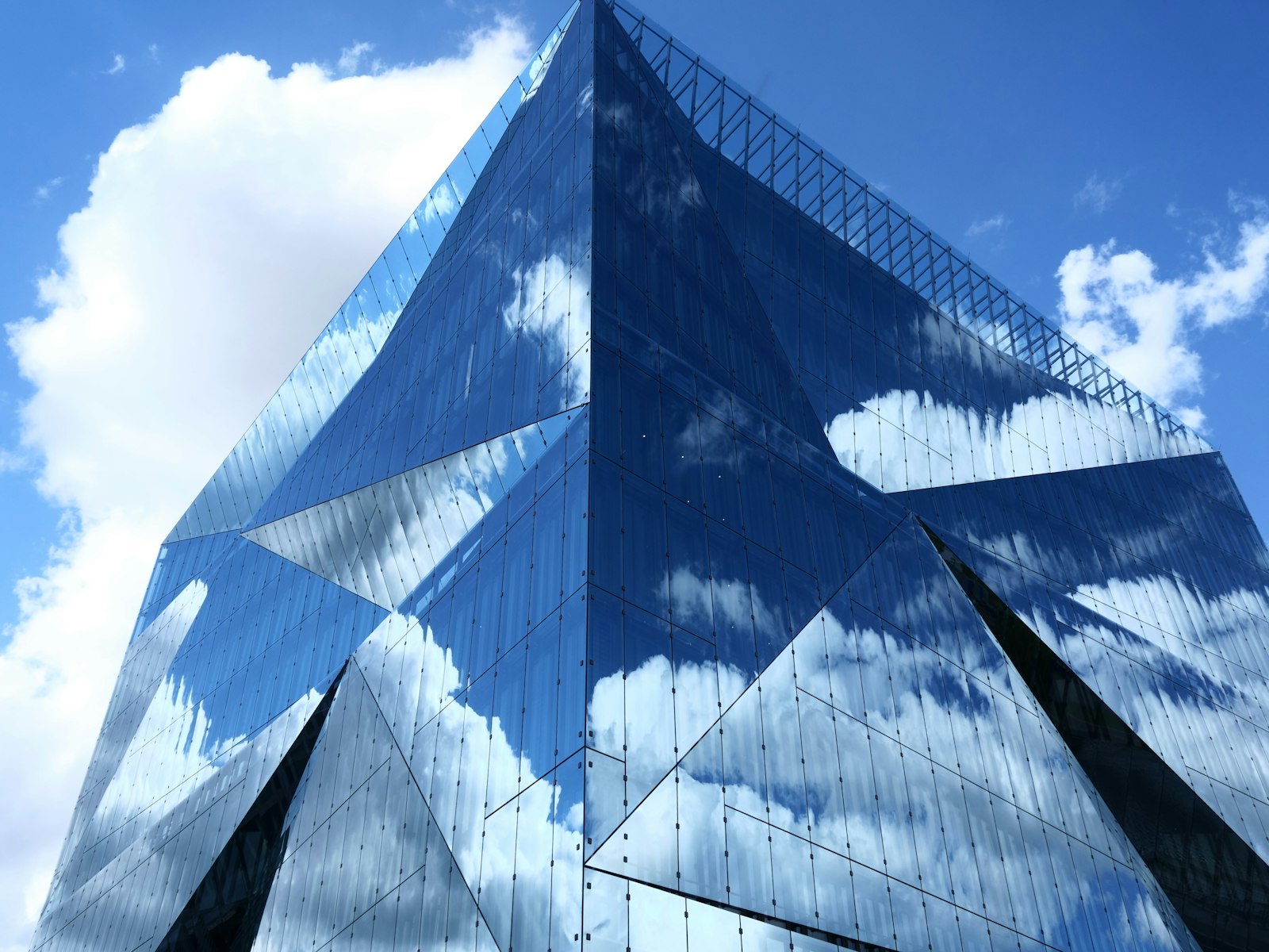 A mirrored-glass building reflecting a bright, cloud-filled sky