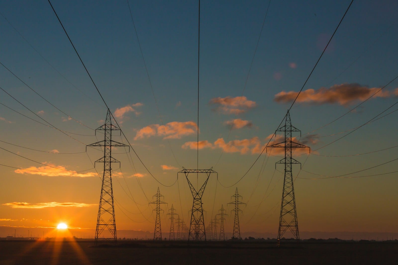 High-voltage electricity transmission towers silhouetted at dusk