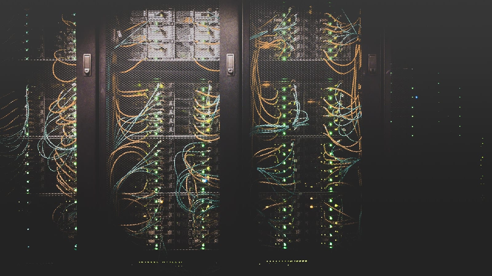 Rows of servers in a data centre, dense with orange and teal network cabling