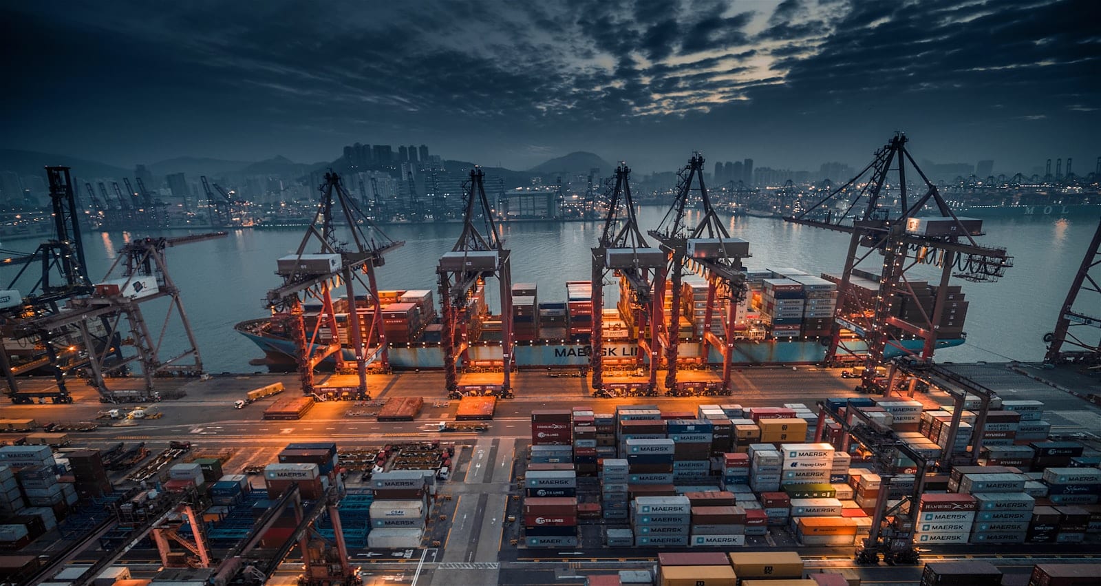 A container shipping port with gantry cranes at dusk